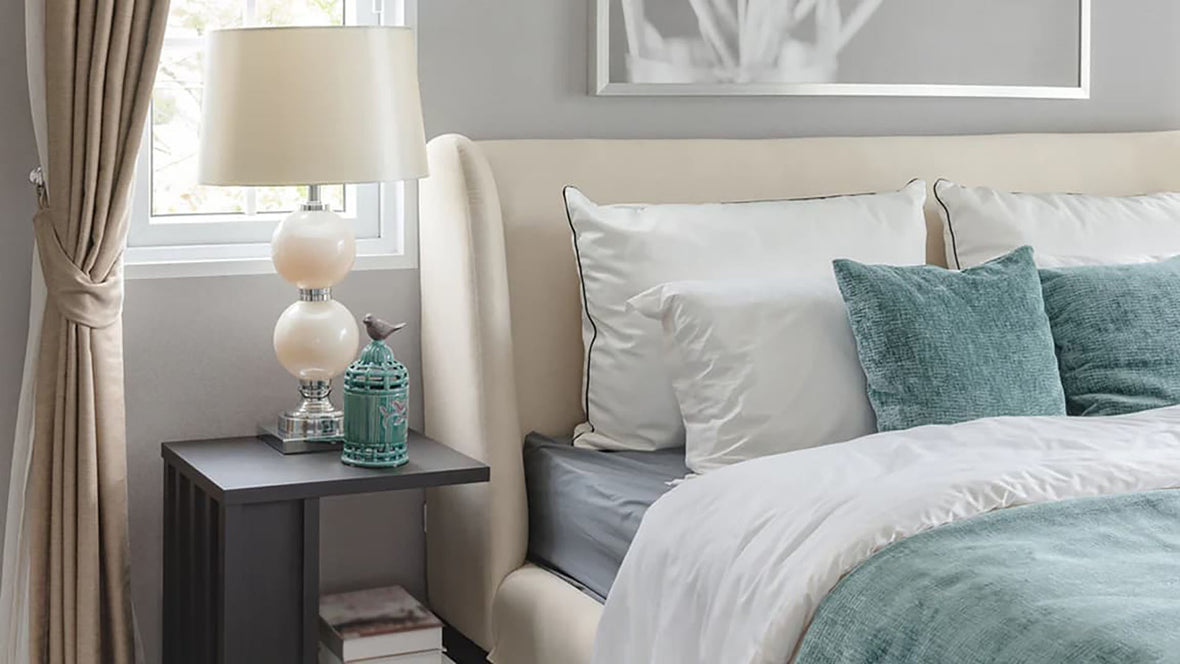 A pearl lamp and matching lamp shade sitting on a night table next to a bed in an elegant bedroom.