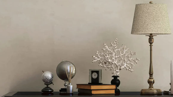 A black dresser with an elegant lamp and lampshade sitting on top