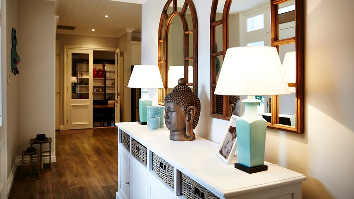 Two matching lamps and lampshades sitting on top of a book shelf in a hallway inside a home.