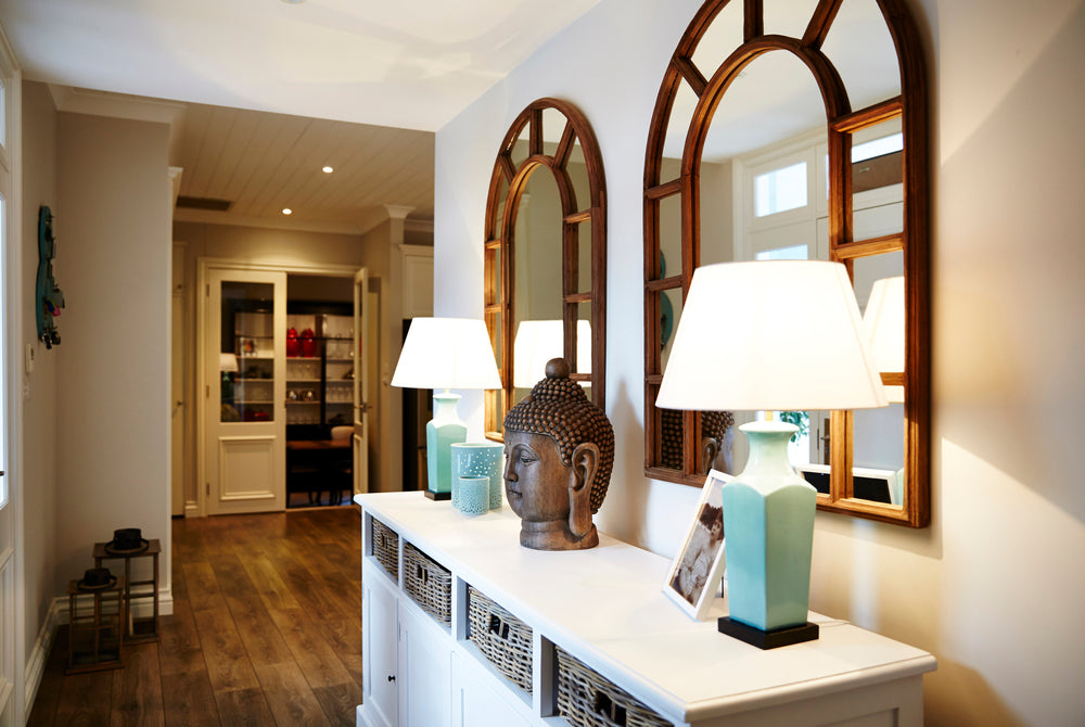 Two matching lamps and lampshades sitting on top of a book shelf in a hallway inside a home.