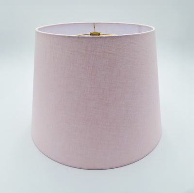 The Linen British Empire (Rolled Edges) is a plain, pale pink hard-backed lampshade with a simple cylindrical shape. The metal fixture inside is partially visible at the top, shown against a white background.