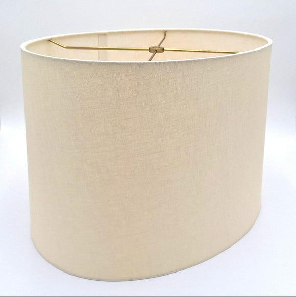 A tapered eggshell linen oval lampshade with rolled edges and brass spider hardware, shown against a plain white background.