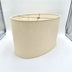 An eggshell linen retro oval lampshade with rolled edges and a warm translucent finish, shown against a plain white background.